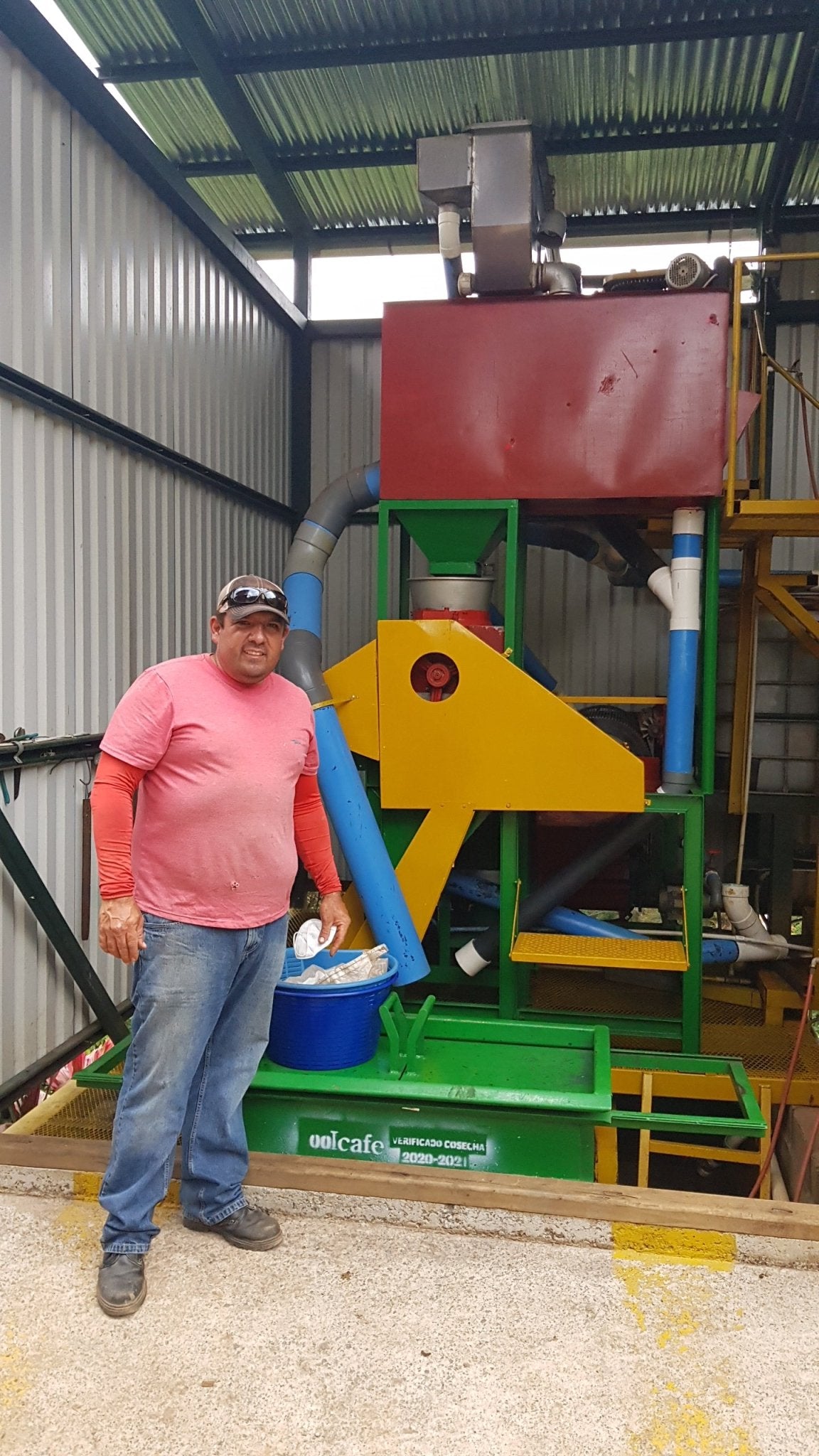 Man stands by coffee processing machine.